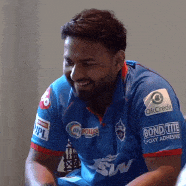 a man wearing a blue shirt that says okcredit on the sleeve