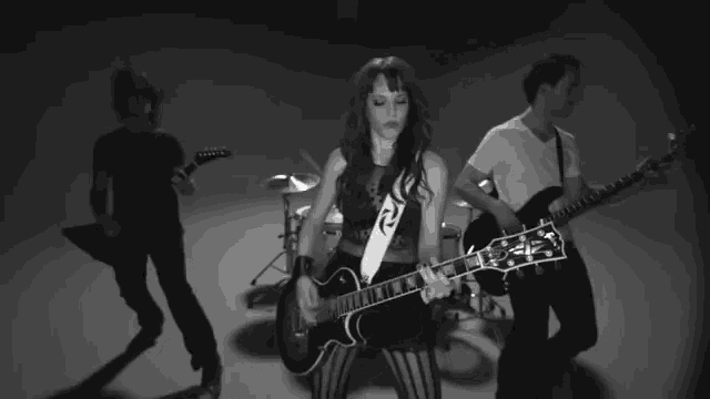 a black and white photo of a band with a woman playing a guitar