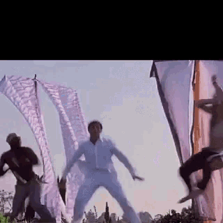 a group of men are dancing in a field with purple flags behind them