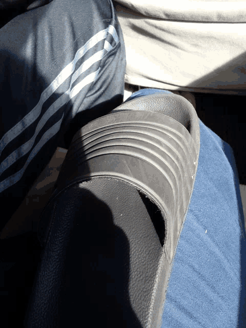 a person wearing a pair of black adidas slides on their leg