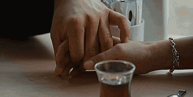 a person holding another person 's hand next to a cup of coffee