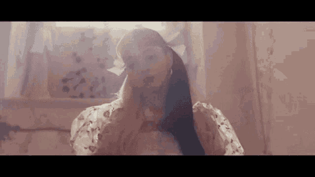 a woman in a pink dress is sitting in a room with a window .