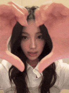 a girl is making a heart shape with her hands