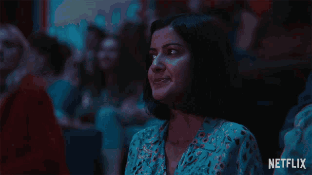 a woman in a blue shirt is clapping in front of a netflix sign