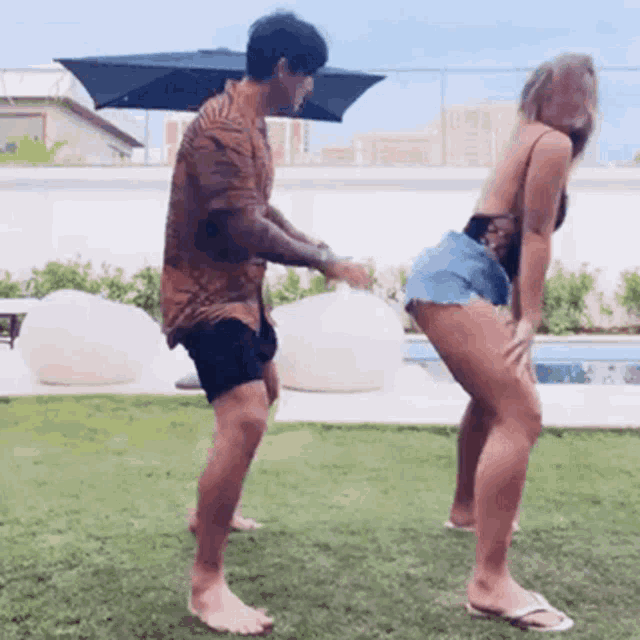 a man is standing next to a woman who is dancing in the grass