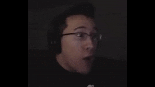 a man wearing glasses and headphones is making a surprised face .