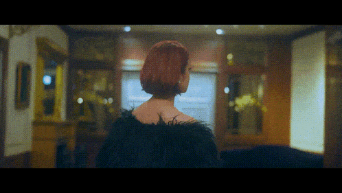 a woman with red hair is wearing a black feathered coat
