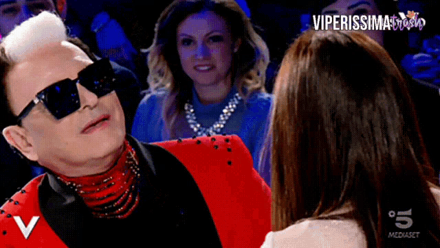 a man in a red suit and sunglasses is talking to a woman on a tv show called viperissimo