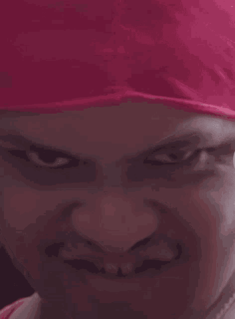a close up of a person 's face with a pink head scarf on
