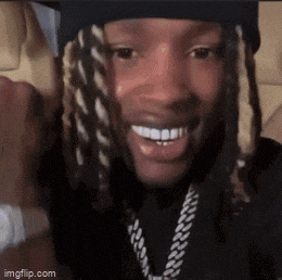 a man with dreadlocks is smiling and wearing a hat and a chain .