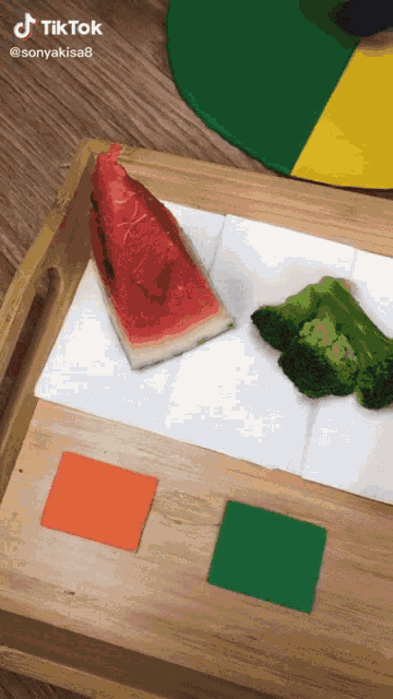 a slice of watermelon and a slice of broccoli on a wooden tray with tiktok written on the bottom