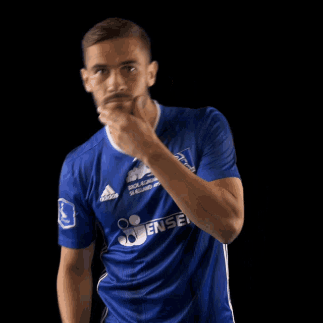 a man wearing a blue adidas shirt is making a funny face