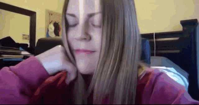 a woman with her eyes closed is wearing a purple sweatshirt .