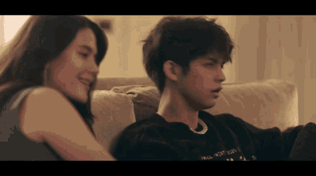 a man and a woman are sitting on a couch and the man is wearing a shirt that says " all that i am "