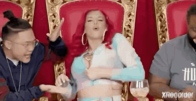 a woman with red hair is sitting on a throne surrounded by two men .