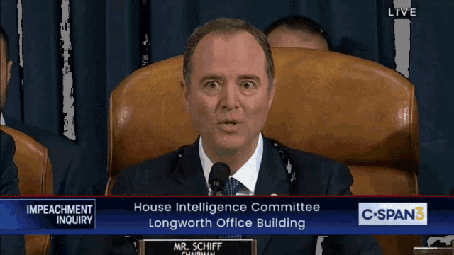 a man in a suit and tie is giving a speech in front of a screen that says impeachment inquiry