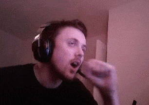 a man wearing headphones and a microphone is singing into a microphone while playing a video game .