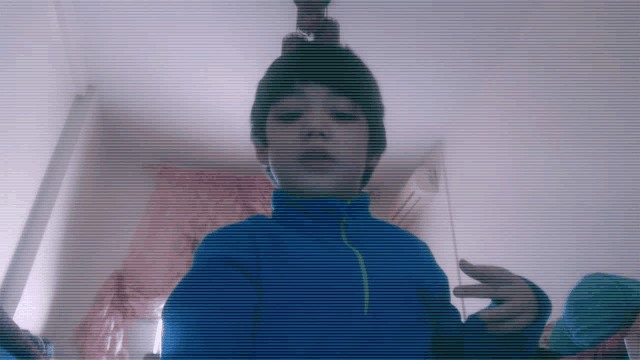 a boy wearing a blue jacket and a beanie is taking a selfie