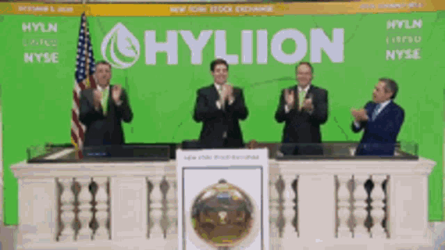a group of men are applauding in front of a hyliion sign