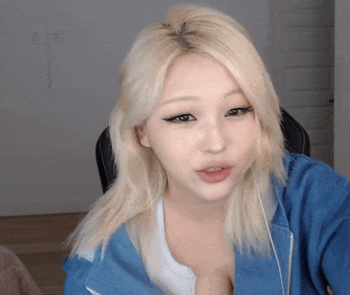 a woman with blonde hair is wearing a blue jacket and white shirt