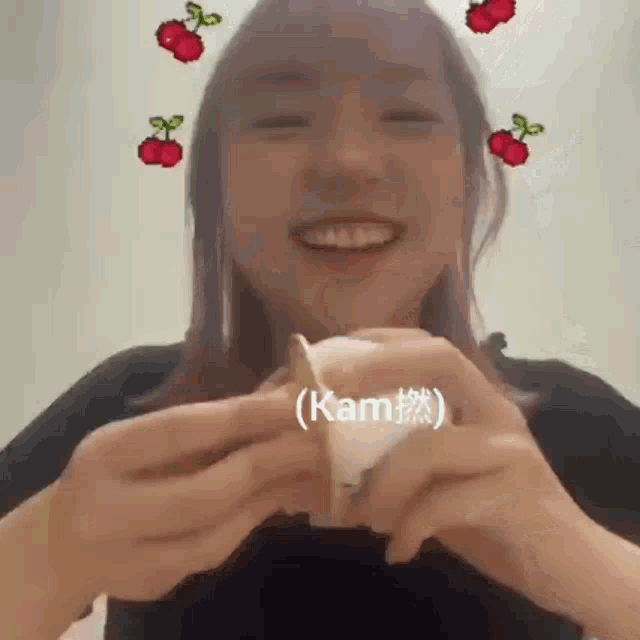 a woman is smiling and holding a piece of food with cherry stickers on her face .