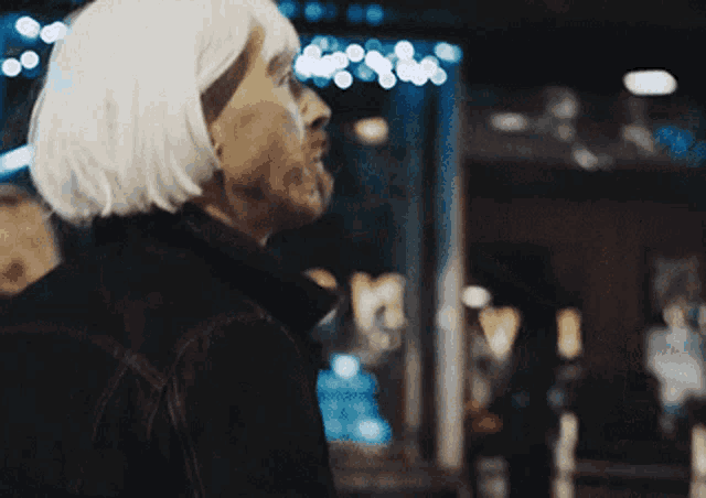 a blurry picture of a woman with white hair and a black jacket