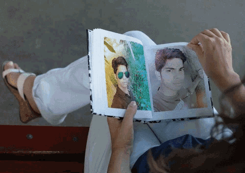 a woman is reading a book with a picture of a man wearing sunglasses on it