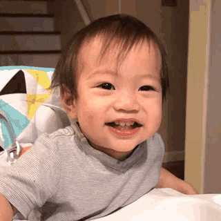 a baby is sitting in a high chair and smiling at the camera