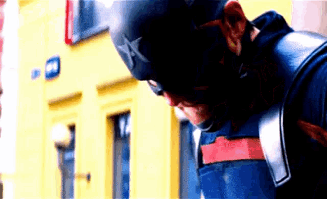 a close up of a man in a captain america costume standing in front of a building .