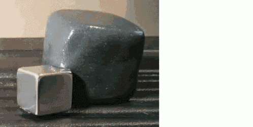 a metal cube is sitting on top of a rock on a wooden table .