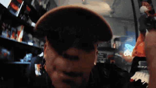 a blurry picture of a man wearing a hat with a neon sign behind him that says ' a ' on it