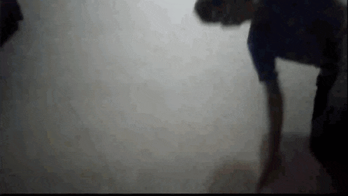 a man in a blue shirt is standing in a dark room .