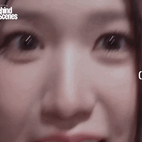 a close up of a woman 's face with the words behind scenes on the bottom right