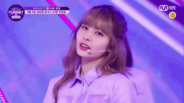 a girl in a purple shirt stands in front of a mnet banner