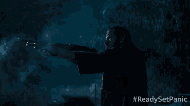 a man is holding a shotgun in the dark with #readysetpanic written on the bottom