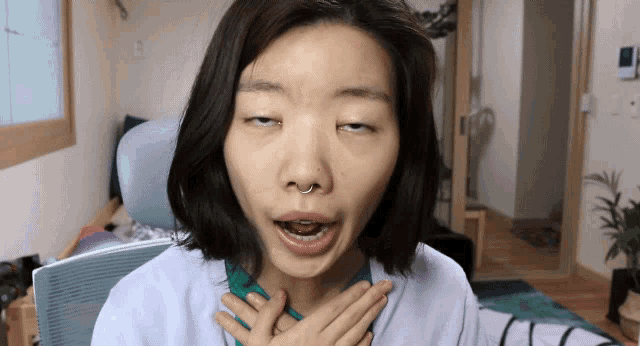 a woman with a nose ring is making a funny face with her hands on her chest