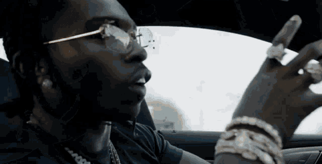 a man wearing glasses and a ring is sitting in a car .