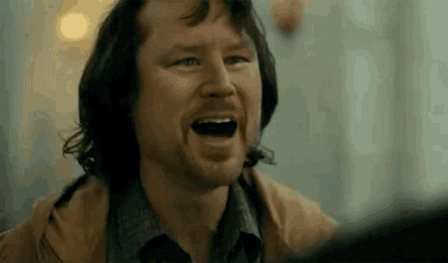 a man with a beard is laughing with his mouth wide open .