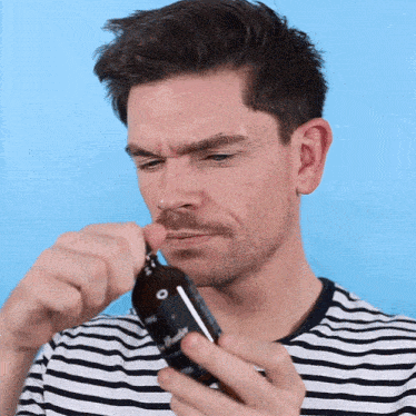 a man in a striped shirt is holding a bottle that says ' o ' on it