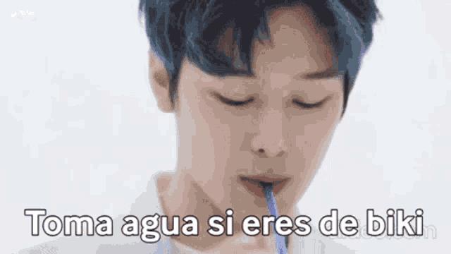 a young man is drinking water from a straw .