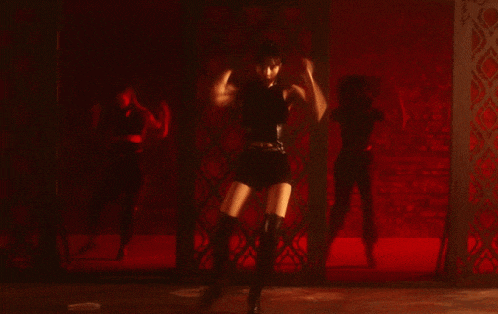 a woman is dancing in a dark room with a red background .