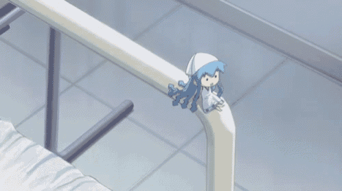 a doll with blue hair is sitting on the railing of a bed