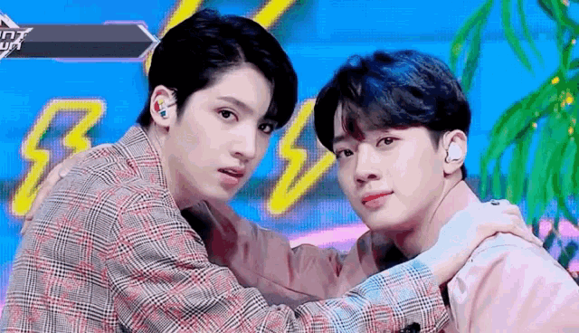 two young men are standing next to each other on a stage .
