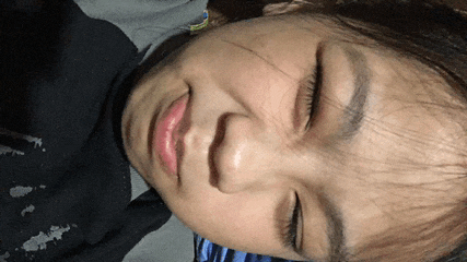 a close up of a person 's face with their eyes closed and a black shirt on