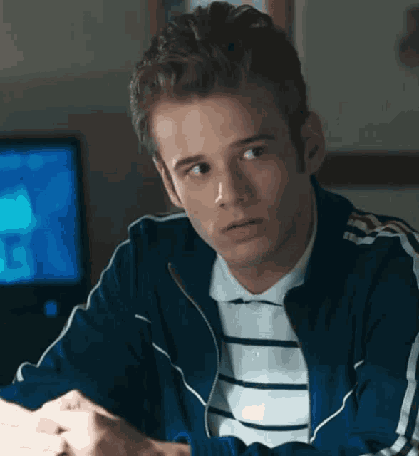 a young man wearing a blue adidas jacket and striped shirt