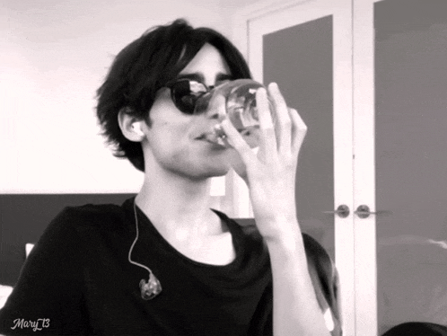 a black and white photo of a man drinking from a glass with mary13 written on the bottom right