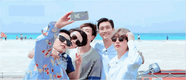 a group of young men are taking a picture of themselves on the beach .