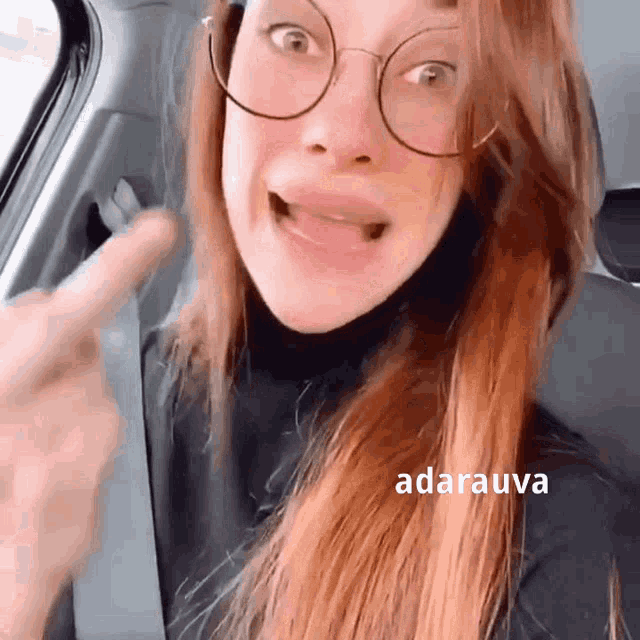 a woman wearing glasses is sitting in the back seat of a car and making a funny face