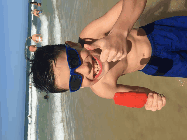 a young boy wearing blue sunglasses is giving a thumbs up