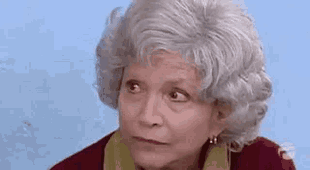 an elderly woman with gray hair and earrings is looking up at the sky .